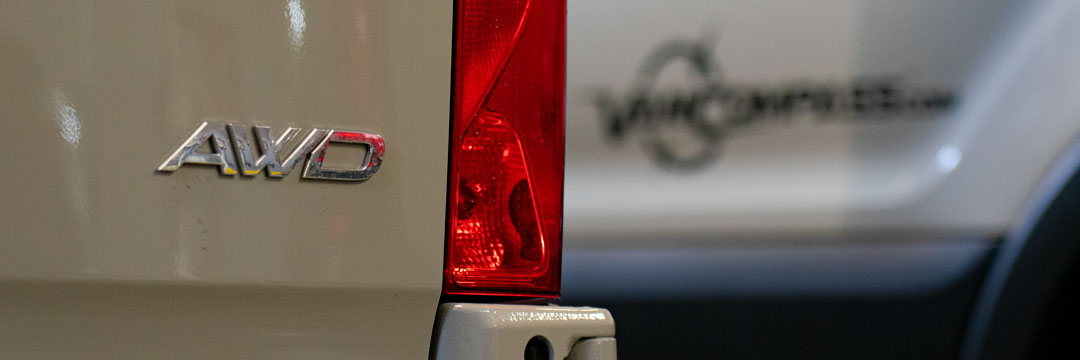 Close-up of the red tail light and logo on the back of a truck, highlighting the vehicle's automotive exterior design.