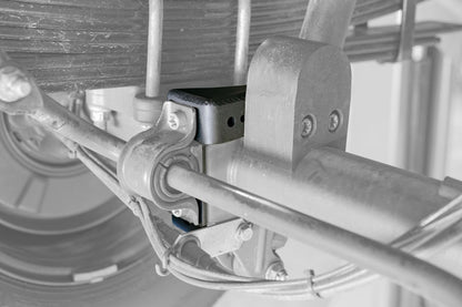Close-up of Baja Sur Heavy Duty Rear Lower Shock Brackets for Sprinter 2500, showcasing robust steel construction and reinforcement design by Van Compass.