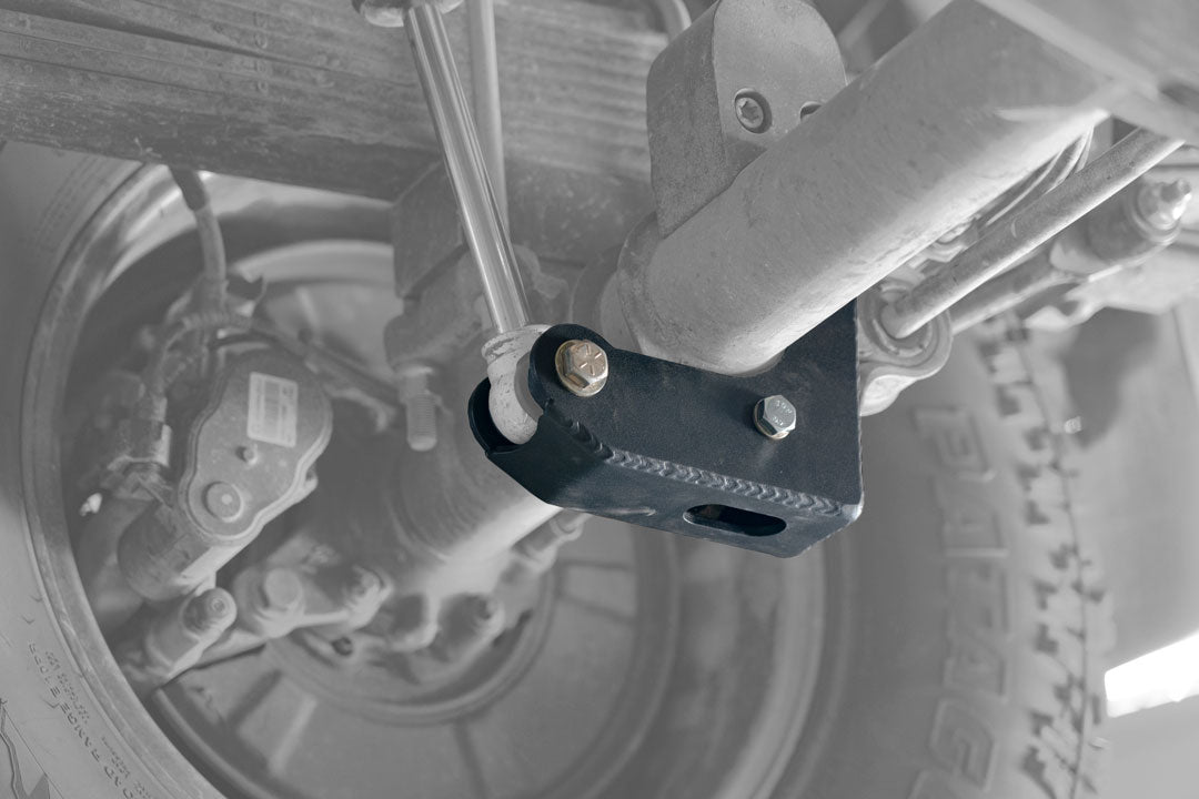 BAJA NORTE HIGH CLEARANCE REAR LOWER SHOCK BRACKETS - SPRINTER 2500, close-up of a metal pipe with a black bracket designed for increased clearance.