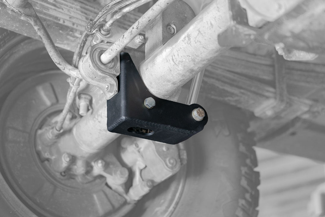 BAJA NORTE HIGH CLEARANCE REAR LOWER SHOCK BRACKETS - SPRINTER 2500 (2007-PRESENT) by VAN COMPASS, featuring heavy-duty black metal brackets with bolts and nuts for enhanced ground clearance.
