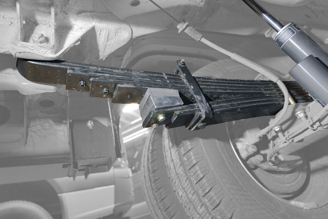 Close-up of a metal shock absorber from the STAGE 4.3 DUALLY SYSTEM - SPRINTER AWD, 4X4 (2015-PRESENT 3500) by VAN COMPASS attached to a tire.