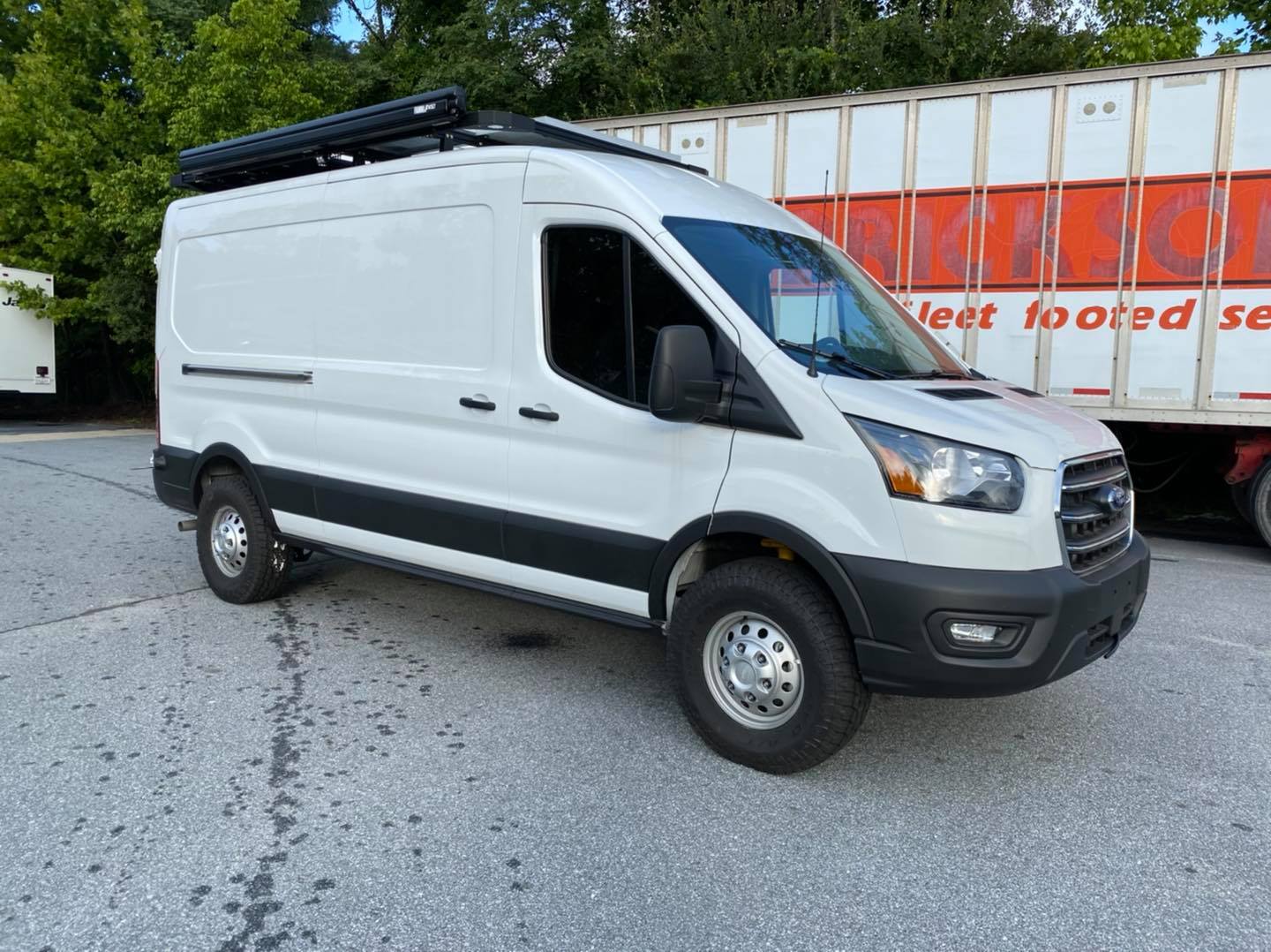 White van equipped with Stage 2 Topo 2.0 System for Ford Transit AWD, featuring 2 lift, adjustable shocks, and improved ride quality for handling rough terrain.
