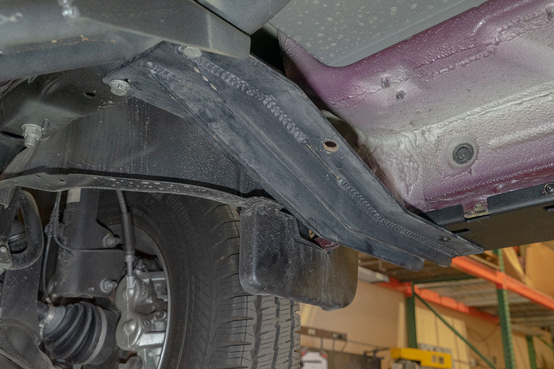 Close-up of Van Compass Rocker Guards for Sprinter 4x4, showing metal frames and integrated Hi-Lift jack slots for enhanced chassis rigidity and protection.