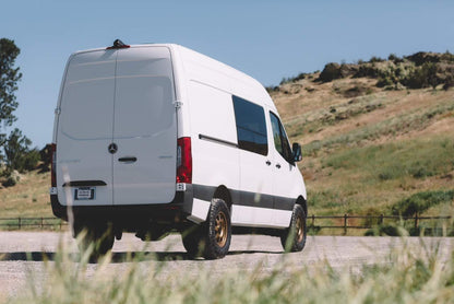 STRIKER 2 Lift Kit - Sprinter 2WD (2019-2022 2500 and 3500) by VAN COMPASS on a white van driving on a dirt road.