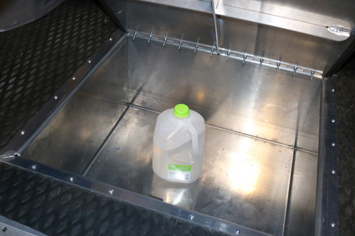 Rear Storage Trunk - Sprinter (2007+) by Van Compass, shown as a metal container for van rear storage, featuring a sealed aluminum design and a green-capped jug inside.