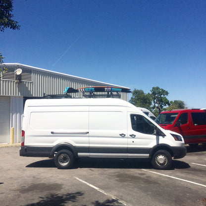 TERRAIN 2 REAR LIFT KIT - TRANSIT (2015+) by VAN COMPASS installed on a white van in a parking lot, showcasing enhanced ground clearance.