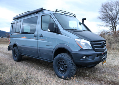 Van equipped with the Striker 4x4 2 Lift Kit parked in a field, showcasing enhanced ground clearance and larger tire compatibility for Sprinter 4x4 models.