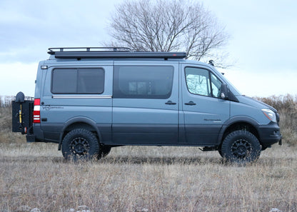 Van Compass Striker 4x4 lift kit installed on a van parked in a field, showcasing increased ground clearance and larger tires for enhanced off-road capability.