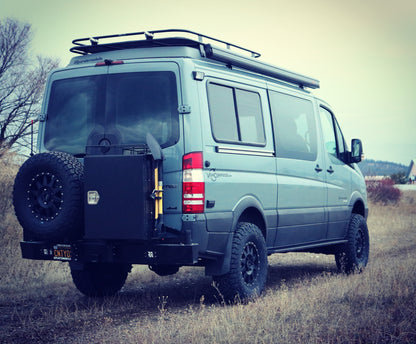 A van parked in a field showcasing the Striker 4x4 lift kit, providing increased clearance for larger tires and enhanced off-road capability for Sprinter 4x4 models.