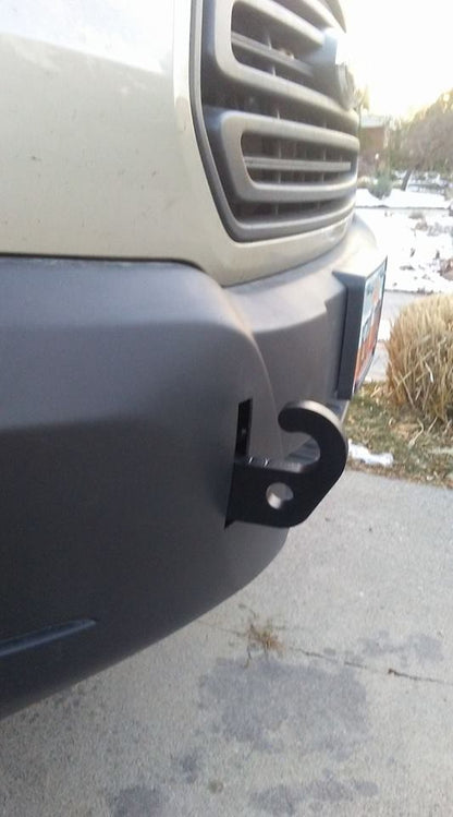 Front Tow Point - Transit (2013+) by Van Compass, shown attached to a car bumper with a d-ring hook for towing, visible through the plastic bumper cover.